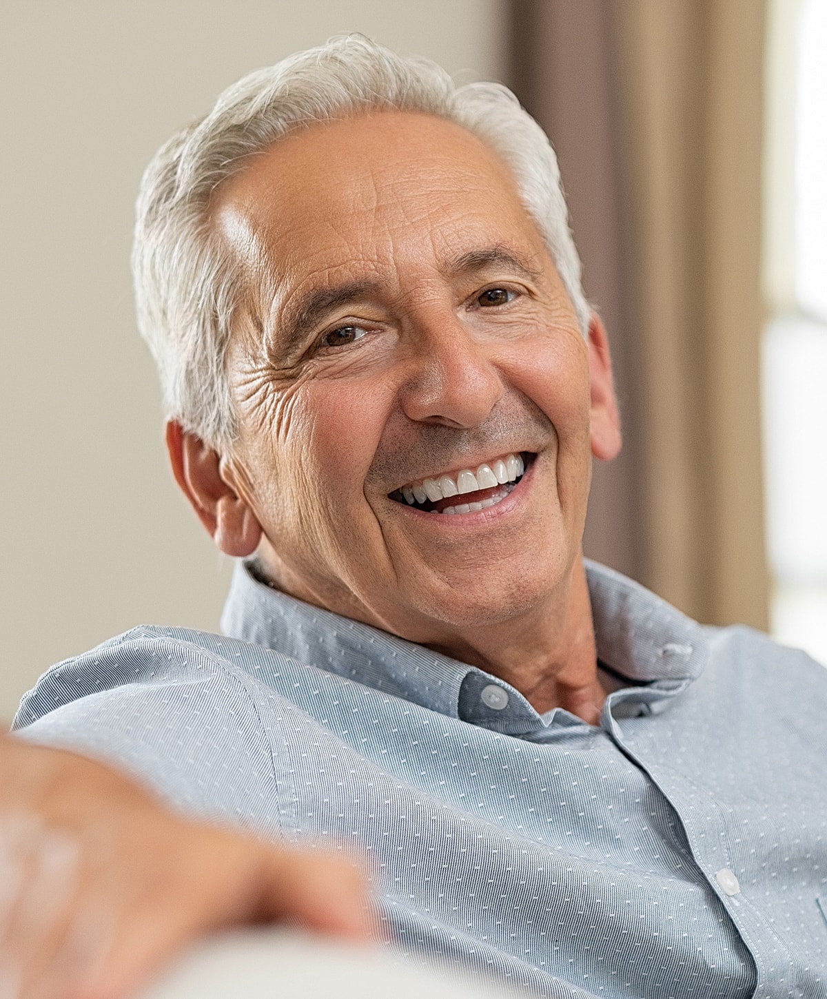 Smiling older man in casual shirt at home.
