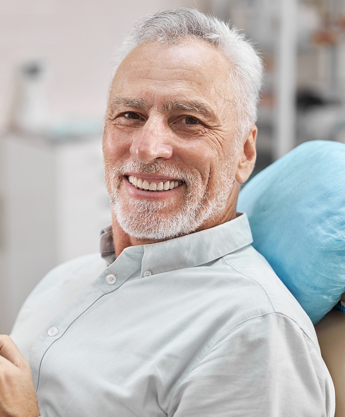 Smiling elderly man in dental office setting.
