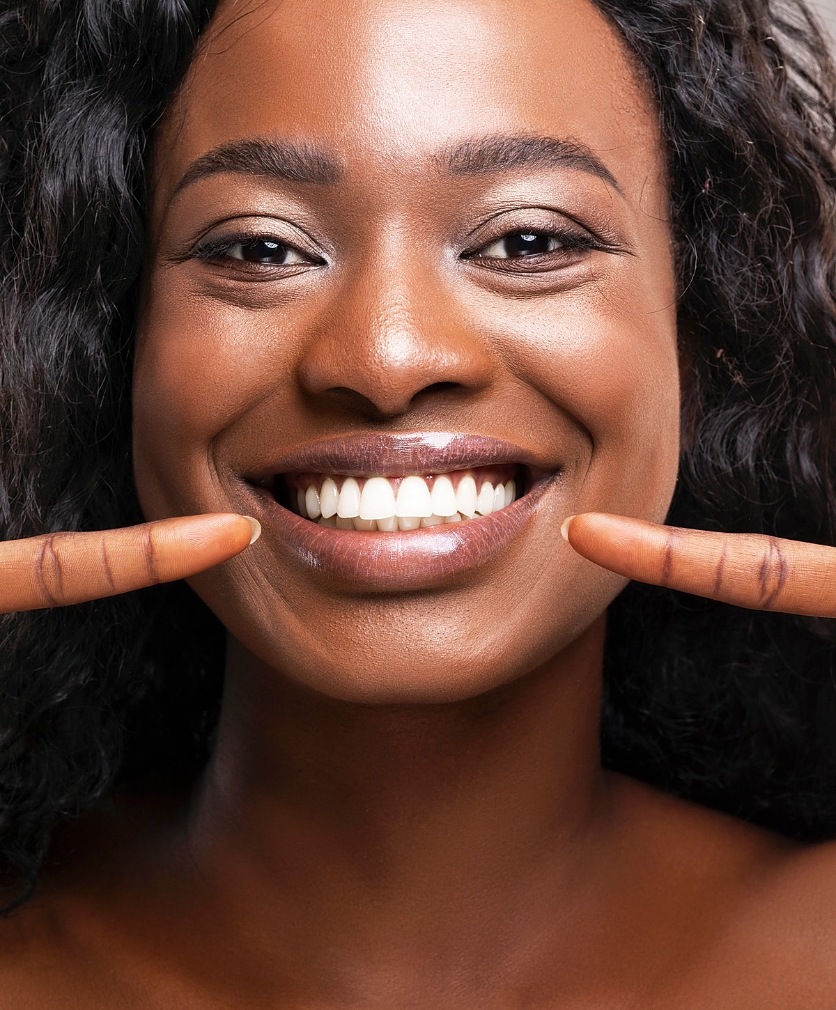 Smiling woman with curly hair showing teeth.