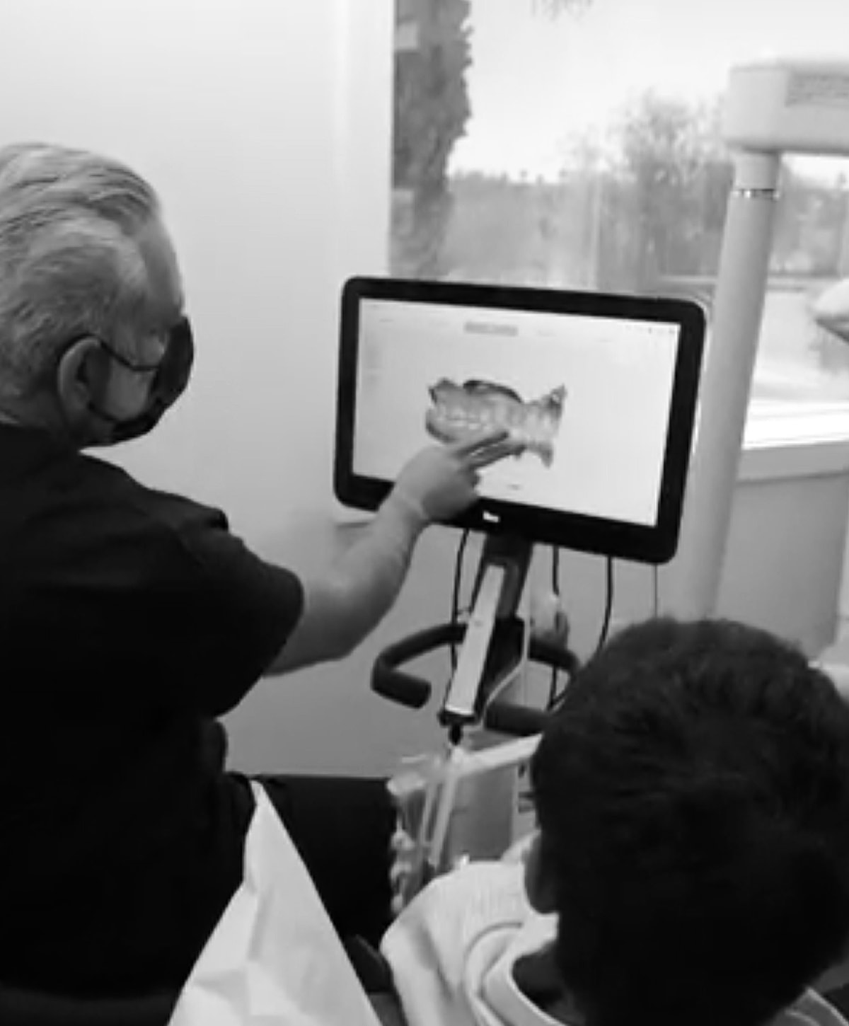 Dentist showing patient an image on screen.