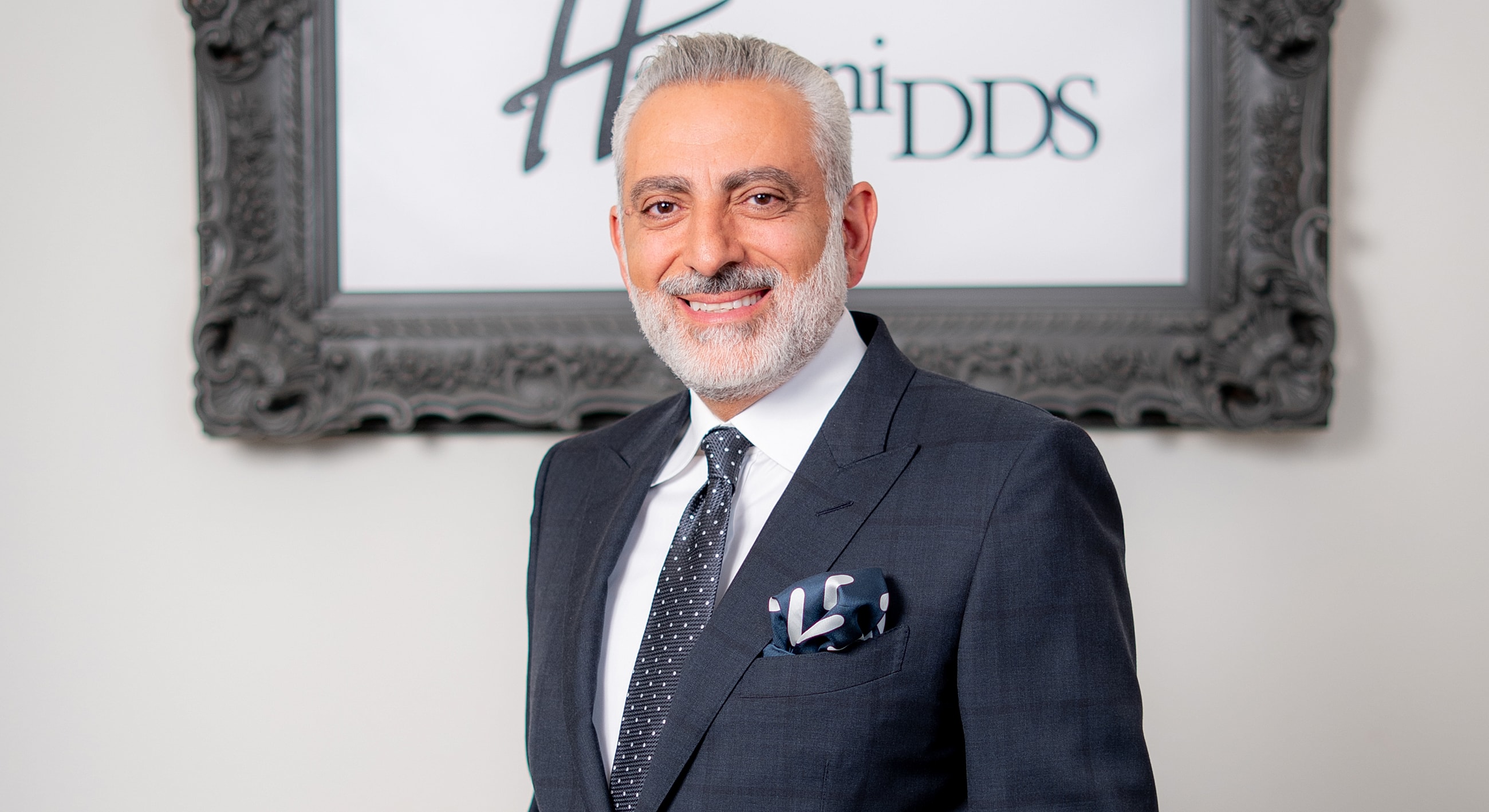 Man in suit smiling in dental office setting.