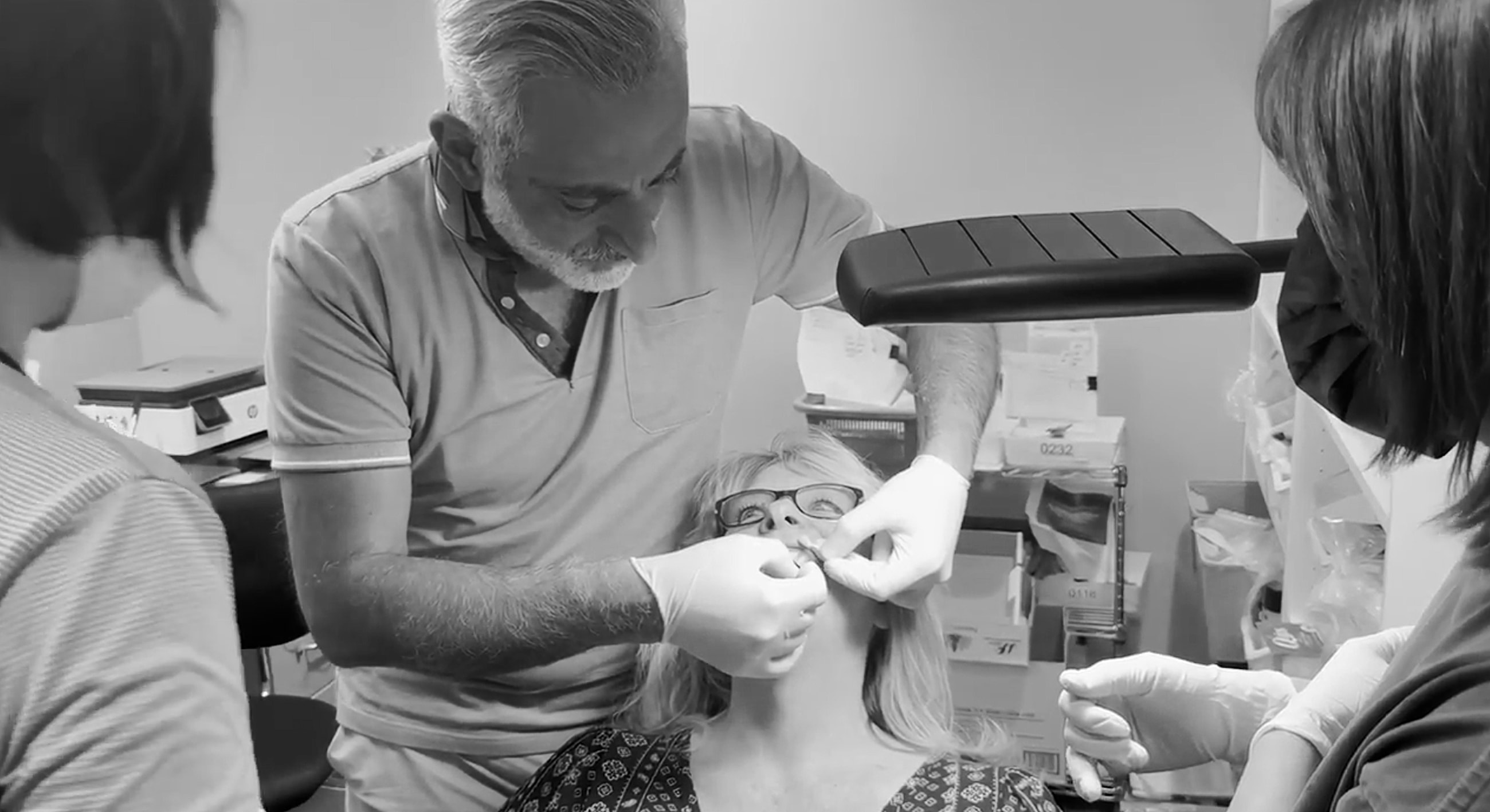 Dental procedure with multiple professionals assisting patient.
