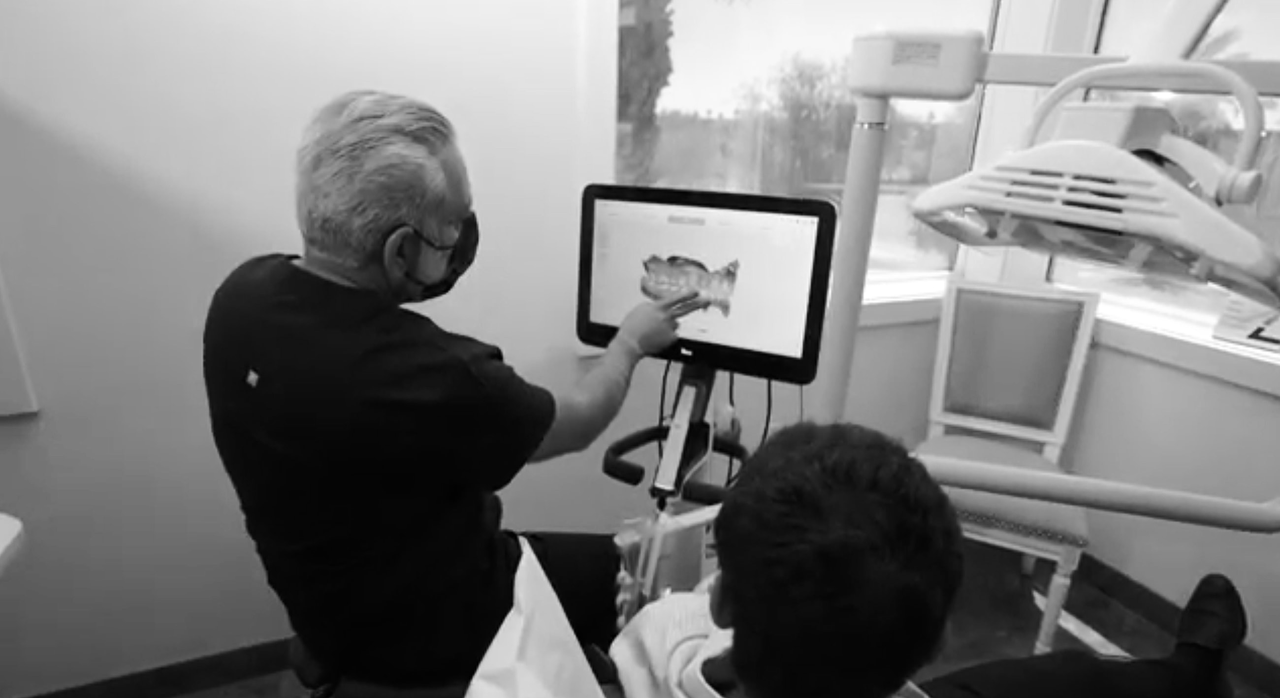 Dentist showing patient an image on screen.