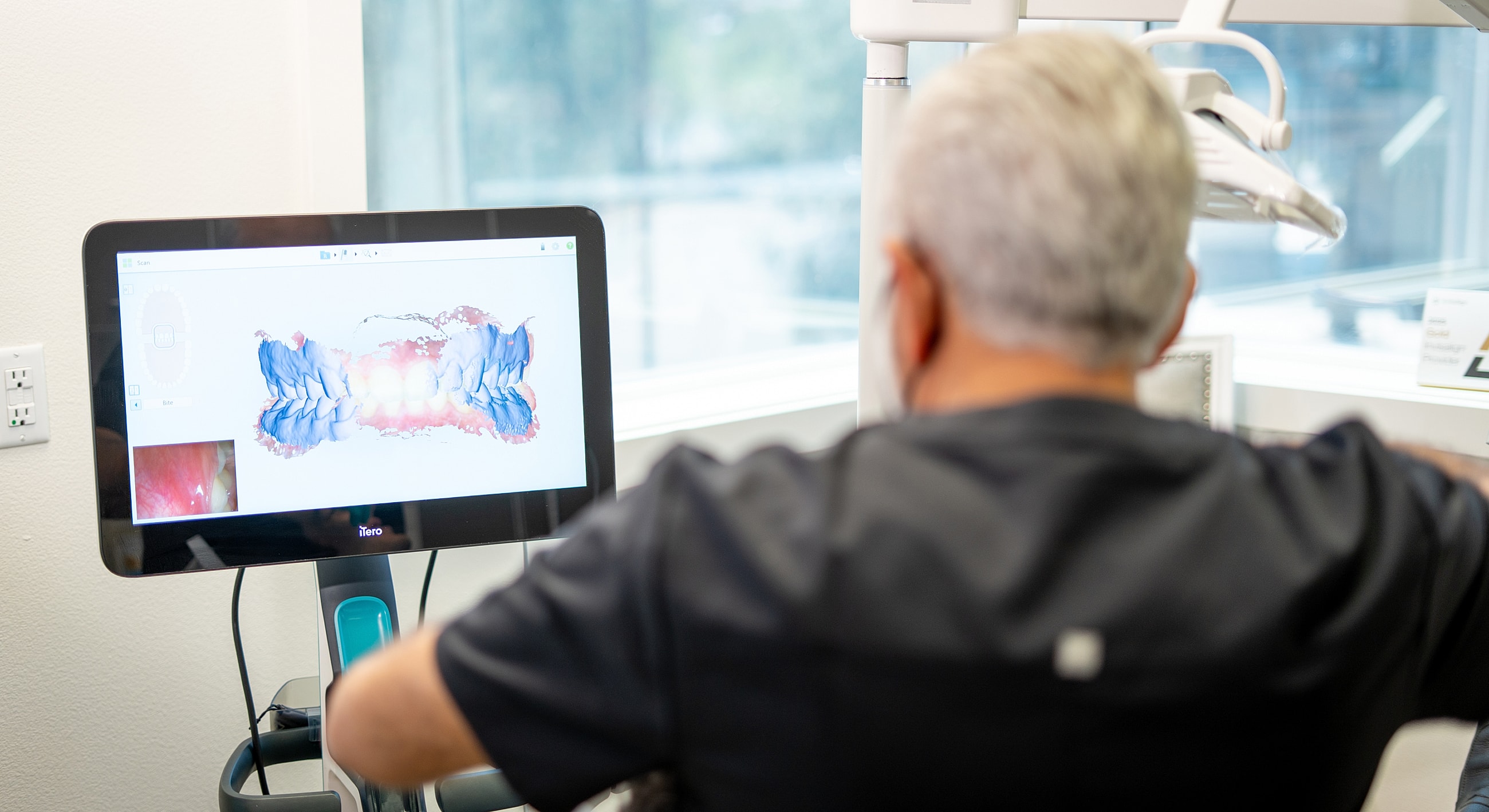 Dental professional reviewing digital scan on monitor