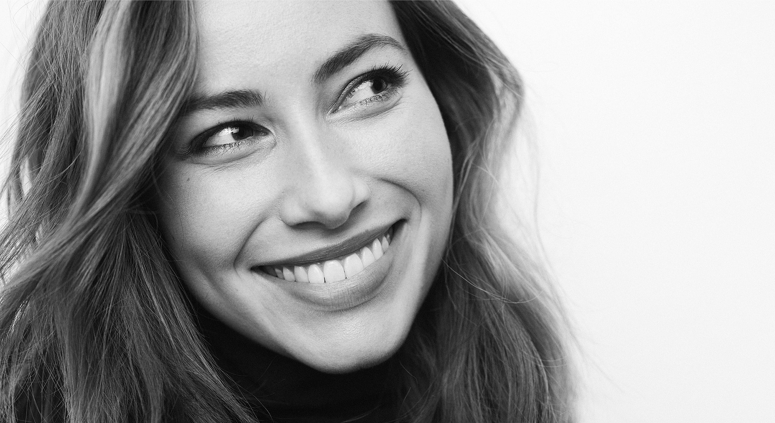 Smiling woman with long hair in black and white.