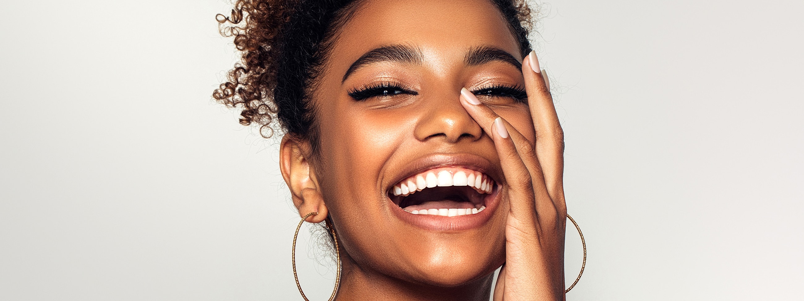 Smiling woman with curly hair against plain background.